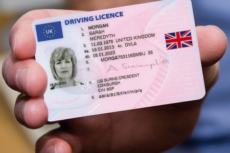 A hand holding a UK driving licence